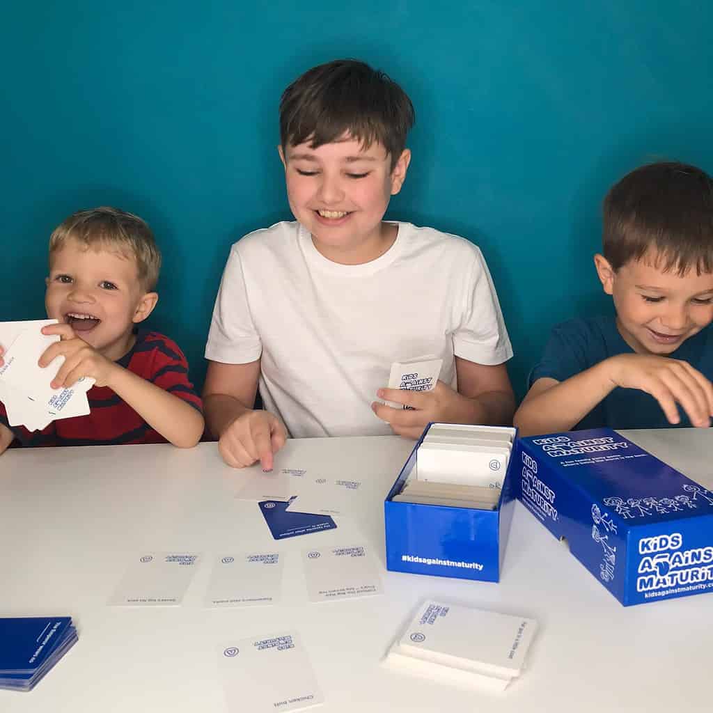 3 boys playing card game Kids Against Maturity