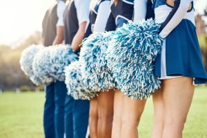 Cheerleader pom poms, backs and students in cheerleading uniform on a outdoor field. Athlete group,