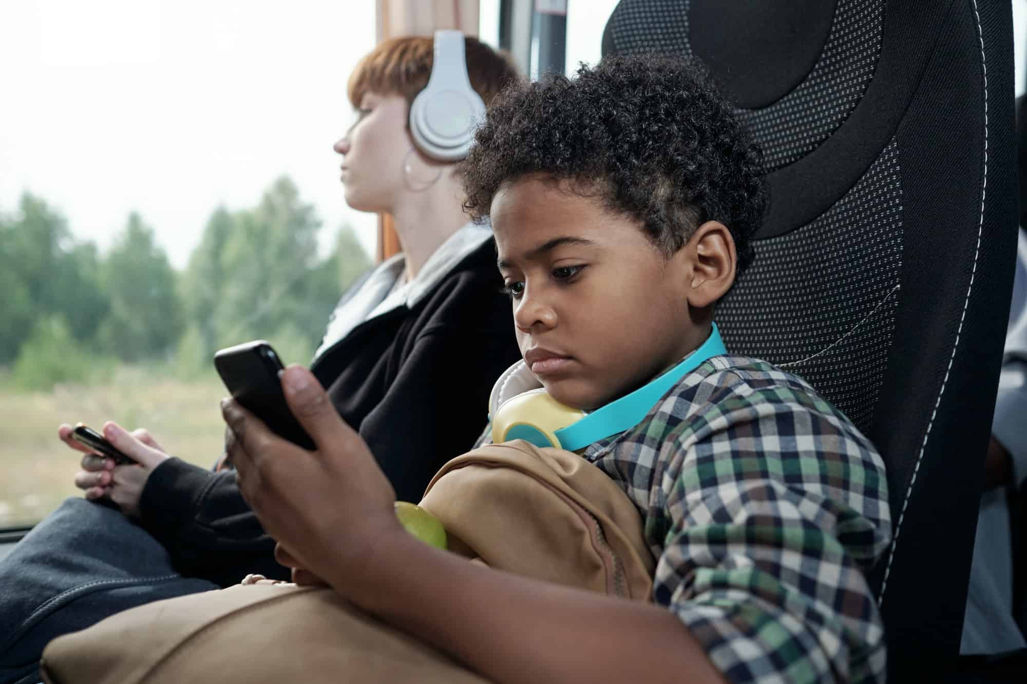 Little boy looking at screen of smartphone in the bus