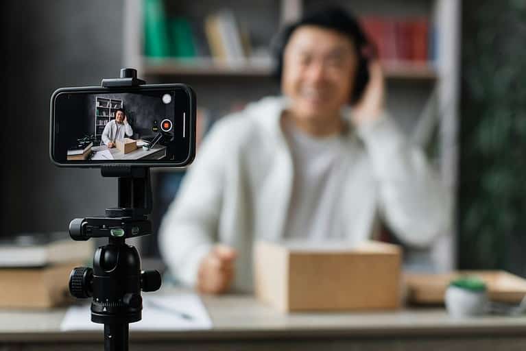 Focuse on smartphone screen, asian man recording video on phone camera while unpacking box